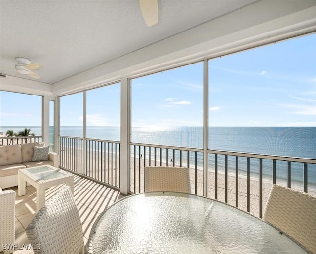 sunroom / solarium with a water view, ceiling fan, and a beach view