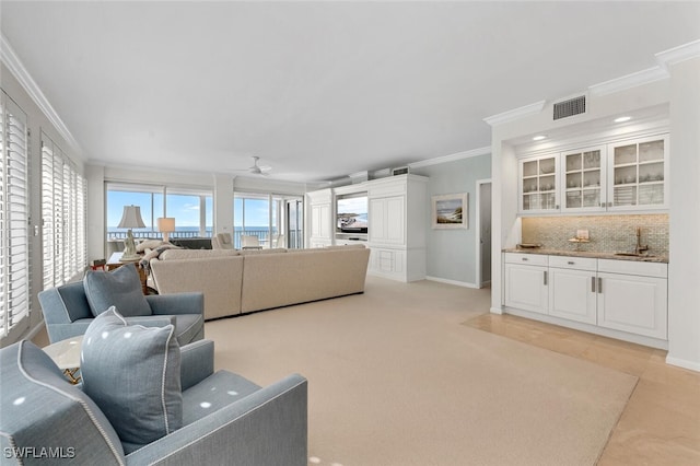 living room featuring ornamental molding, sink, light colored carpet, and ceiling fan