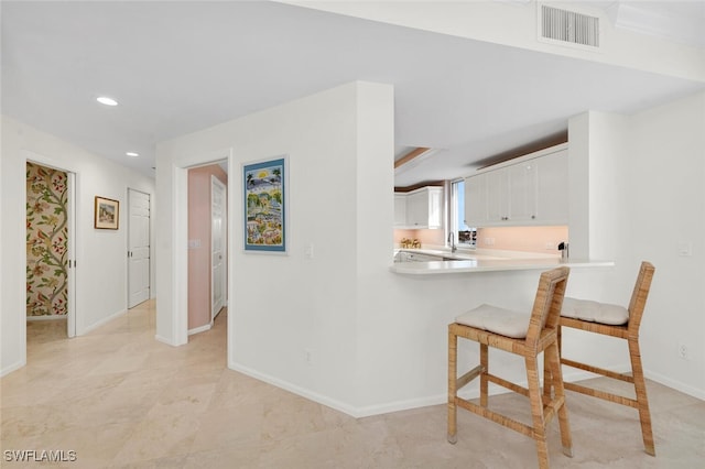 kitchen featuring a breakfast bar, white cabinets, and kitchen peninsula