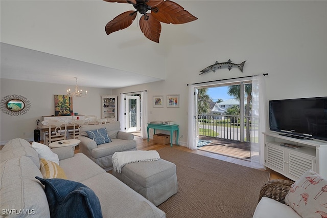 living room featuring hardwood / wood-style floors, ceiling fan with notable chandelier, and a high ceiling