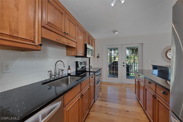 kitchen featuring sink, light hardwood / wood-style flooring, decorative backsplash, stainless steel appliances, and french doors