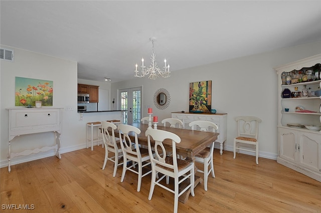 dining area featuring a notable chandelier, light wood-type flooring, and french doors