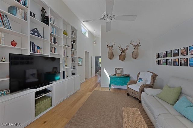 living room with ceiling fan, high vaulted ceiling, and light hardwood / wood-style flooring