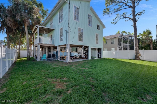 rear view of property featuring a wooden deck, a lanai, and a lawn