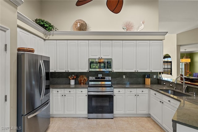 kitchen with sink, light tile patterned floors, appliances with stainless steel finishes, white cabinets, and backsplash