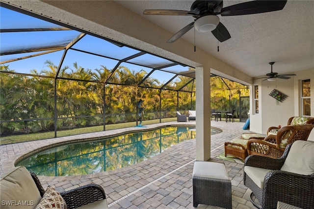 view of swimming pool with an outdoor living space, ceiling fan, glass enclosure, and a patio area