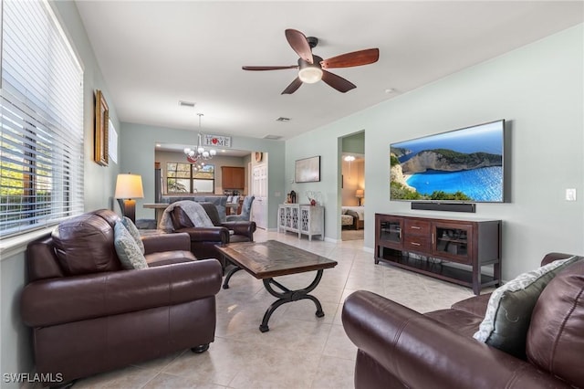 tiled living room featuring ceiling fan with notable chandelier