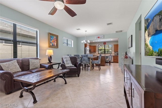 tiled living room with ceiling fan with notable chandelier