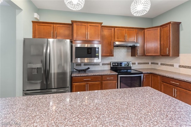 kitchen featuring stainless steel appliances, light stone countertops, and backsplash