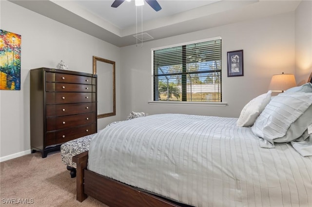 bedroom featuring a tray ceiling, light colored carpet, and ceiling fan