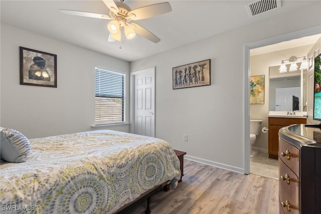 bedroom featuring ensuite bath, light hardwood / wood-style flooring, and ceiling fan