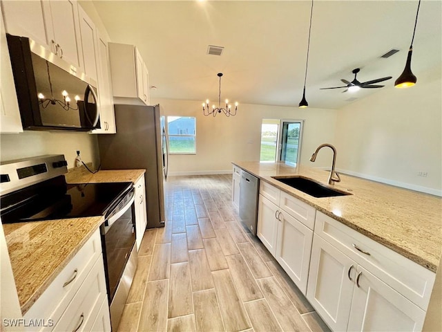 kitchen featuring white cabinetry, appliances with stainless steel finishes, sink, and decorative light fixtures