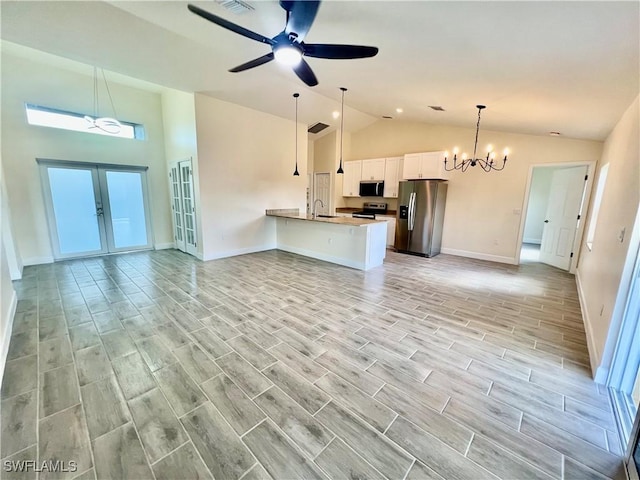 unfurnished living room featuring sink, ceiling fan with notable chandelier, high vaulted ceiling, and french doors