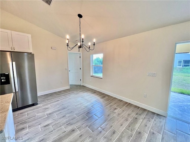 kitchen featuring lofted ceiling, white cabinetry, decorative light fixtures, a chandelier, and stainless steel fridge