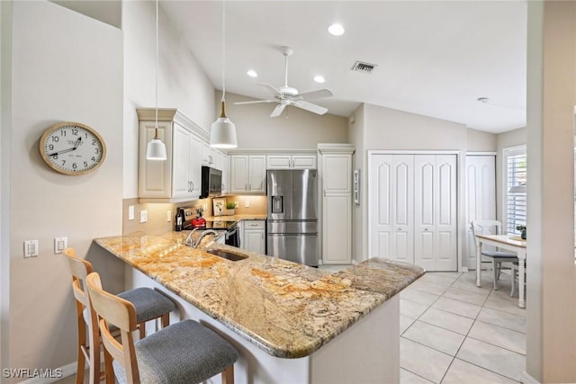 kitchen featuring vaulted ceiling, a breakfast bar, sink, kitchen peninsula, and stainless steel appliances