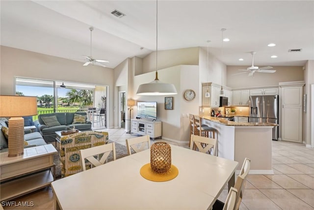 tiled dining area with ceiling fan and high vaulted ceiling