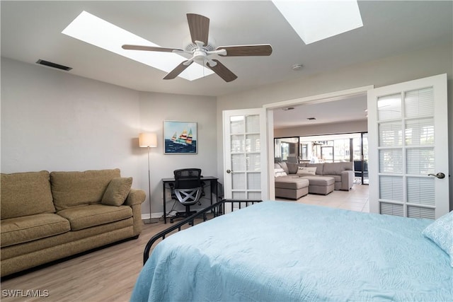 bedroom with ceiling fan, a skylight, and light wood-type flooring