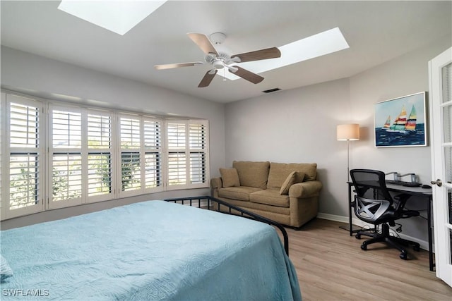 bedroom with ceiling fan, a skylight, and light hardwood / wood-style flooring