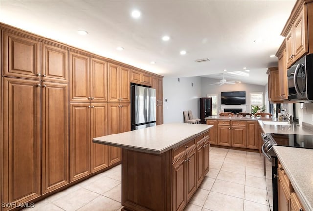 kitchen with lofted ceiling, light tile patterned floors, appliances with stainless steel finishes, kitchen peninsula, and ceiling fan