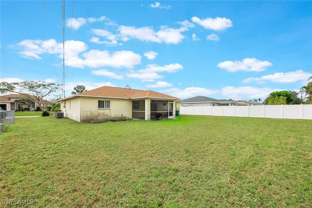 rear view of property featuring a sunroom and a yard