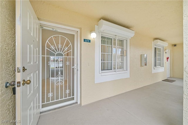 doorway to property with a wall unit AC and stucco siding