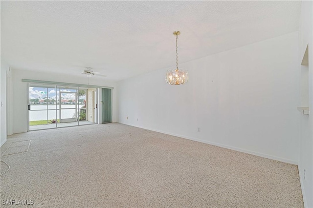 spare room with a textured ceiling, ceiling fan with notable chandelier, carpet flooring, and baseboards