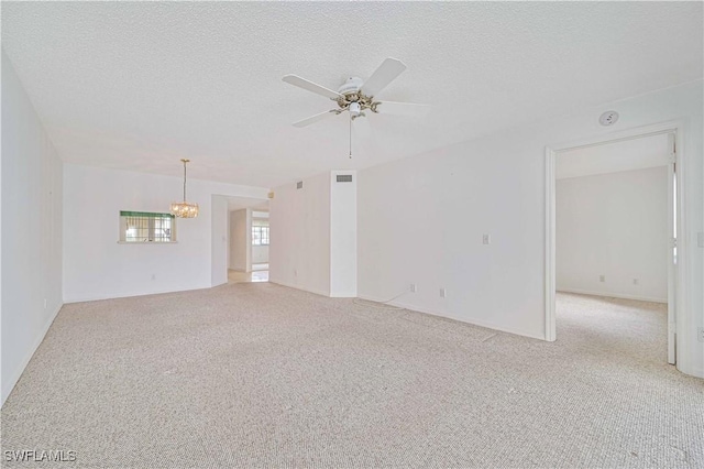 unfurnished room with light colored carpet, a textured ceiling, and ceiling fan with notable chandelier