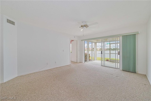 carpeted spare room with visible vents and a ceiling fan