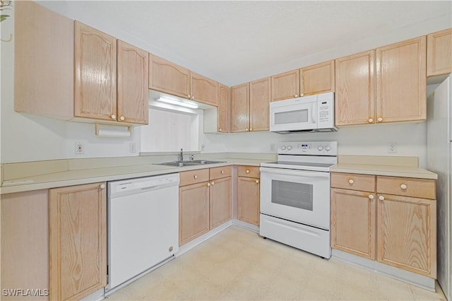 kitchen with light floors, light countertops, light brown cabinetry, a sink, and white appliances