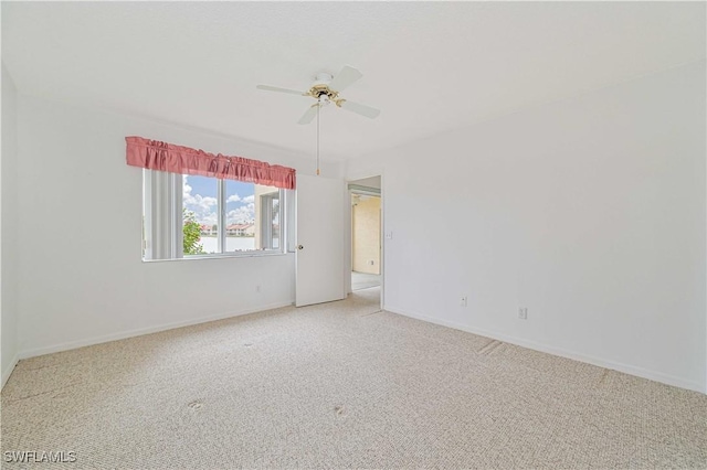 empty room featuring light carpet, a ceiling fan, and baseboards