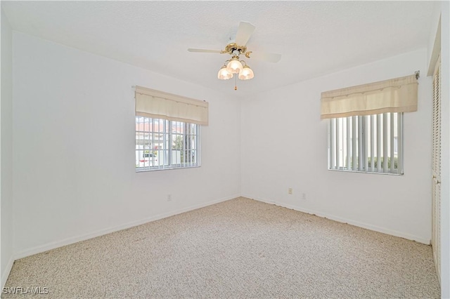 carpeted empty room featuring a ceiling fan and baseboards