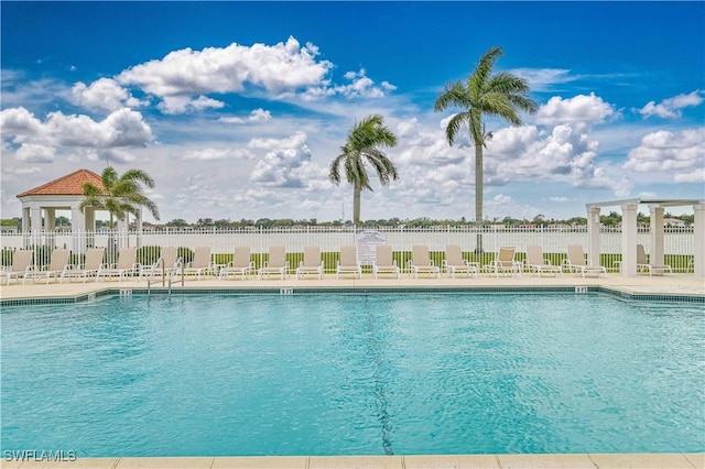 community pool with a patio area and fence