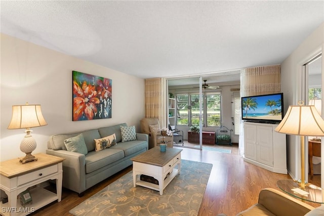 living room featuring ceiling fan, a textured ceiling, and hardwood / wood-style flooring