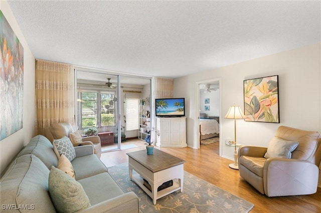 living room featuring hardwood / wood-style flooring, a textured ceiling, and ceiling fan