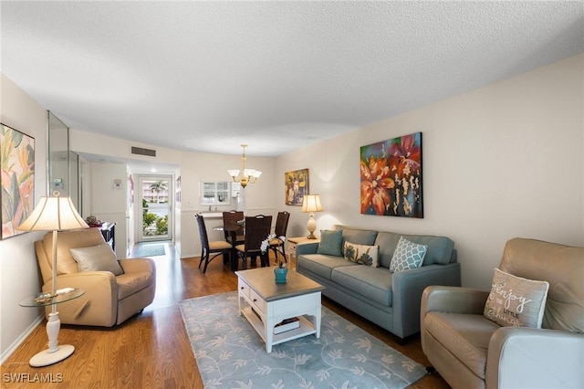 living room featuring a textured ceiling, an inviting chandelier, and hardwood / wood-style flooring