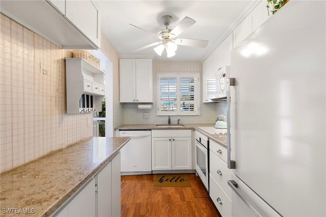 kitchen featuring hardwood / wood-style flooring, white appliances, white cabinets, light stone counters, and sink