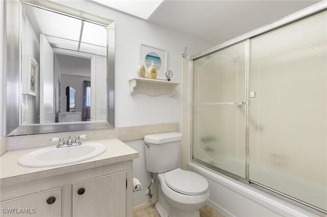 full bathroom with combined bath / shower with glass door, vanity, and toilet