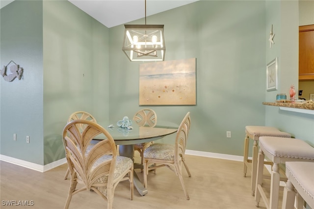 dining space featuring lofted ceiling, an inviting chandelier, and light hardwood / wood-style flooring