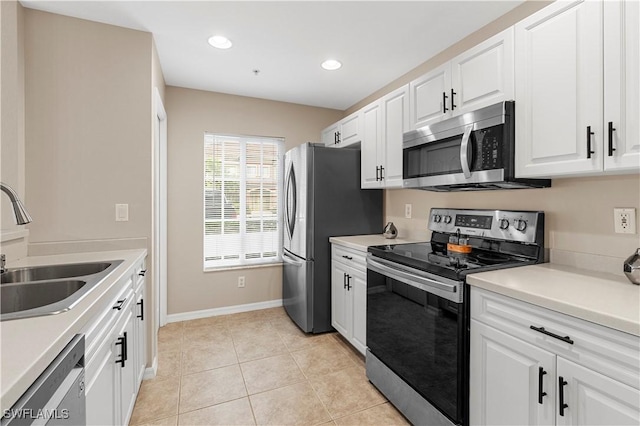 kitchen with light tile patterned floors, appliances with stainless steel finishes, sink, and white cabinets