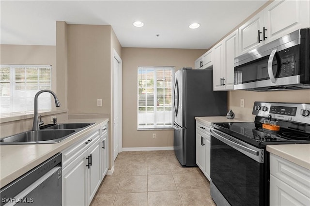 kitchen featuring stainless steel appliances, white cabinetry, sink, and light tile patterned floors