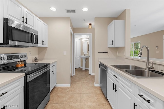 kitchen with white cabinetry, stainless steel appliances, sink, and light tile patterned floors