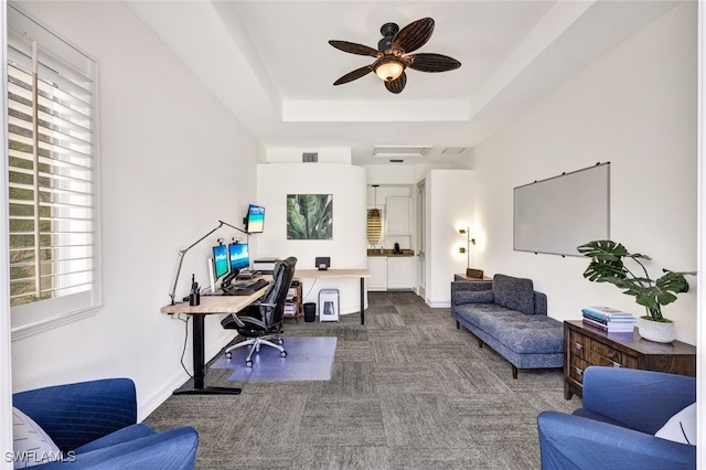 office area featuring a raised ceiling, carpet floors, and ceiling fan