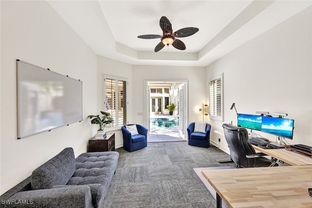 office featuring carpet, ceiling fan, and a tray ceiling