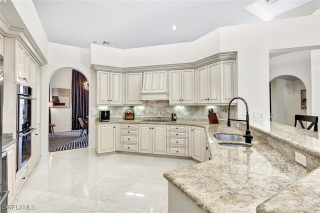 kitchen with black electric cooktop, sink, cream cabinets, and tasteful backsplash