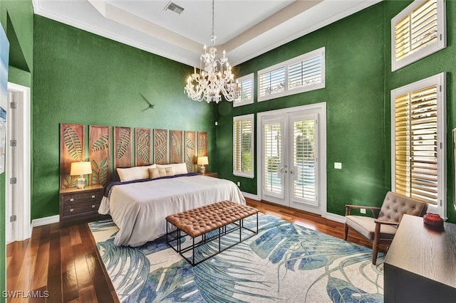 bedroom with french doors, a tray ceiling, dark hardwood / wood-style flooring, a notable chandelier, and access to exterior