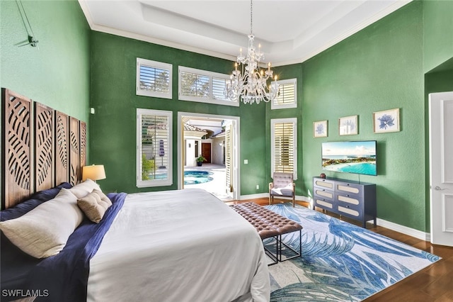 bedroom with a towering ceiling, hardwood / wood-style floors, ornamental molding, a notable chandelier, and a raised ceiling