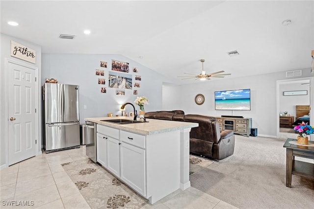 kitchen featuring a sink, white cabinetry, open floor plan, light countertops, and appliances with stainless steel finishes