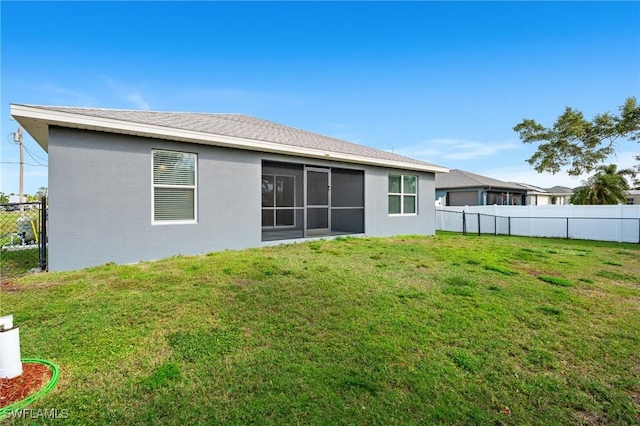 rear view of property with a lawn, fence, and stucco siding