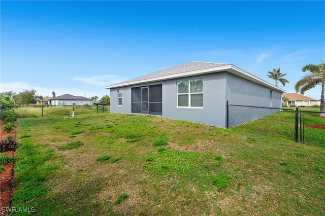 back of property featuring stucco siding, fence, and a yard