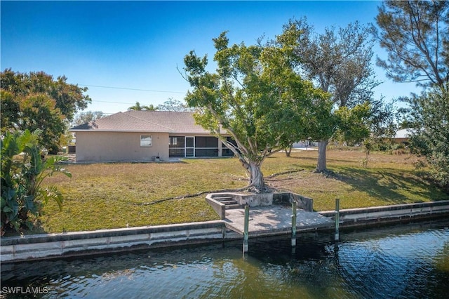 rear view of property with a water view and a lawn